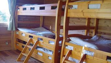 A bunk bed room with wooden walls and a window with curtains.