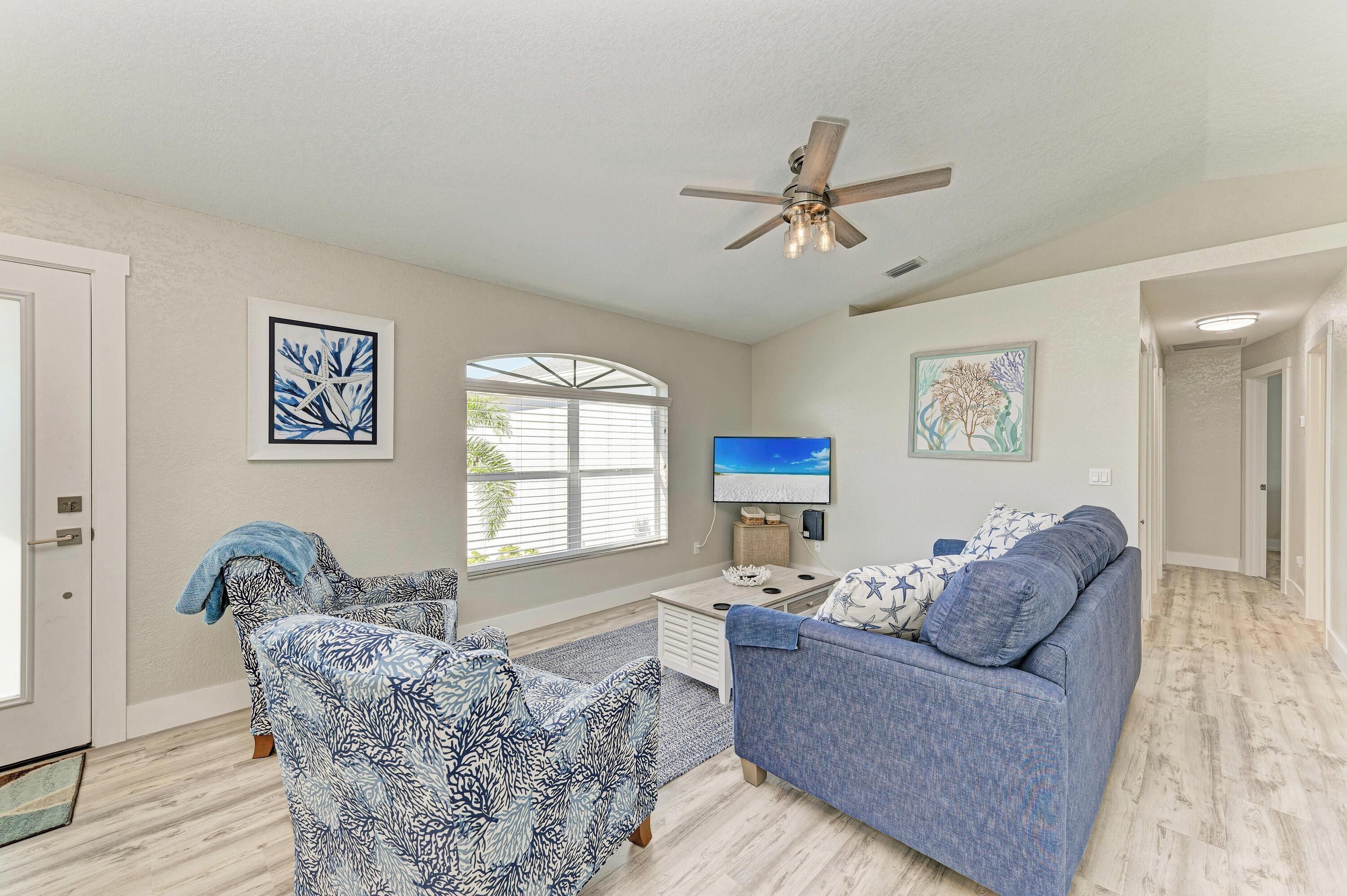 A living room with a ceiling fan, two sofas, a coffee table, and artwork on the walls.