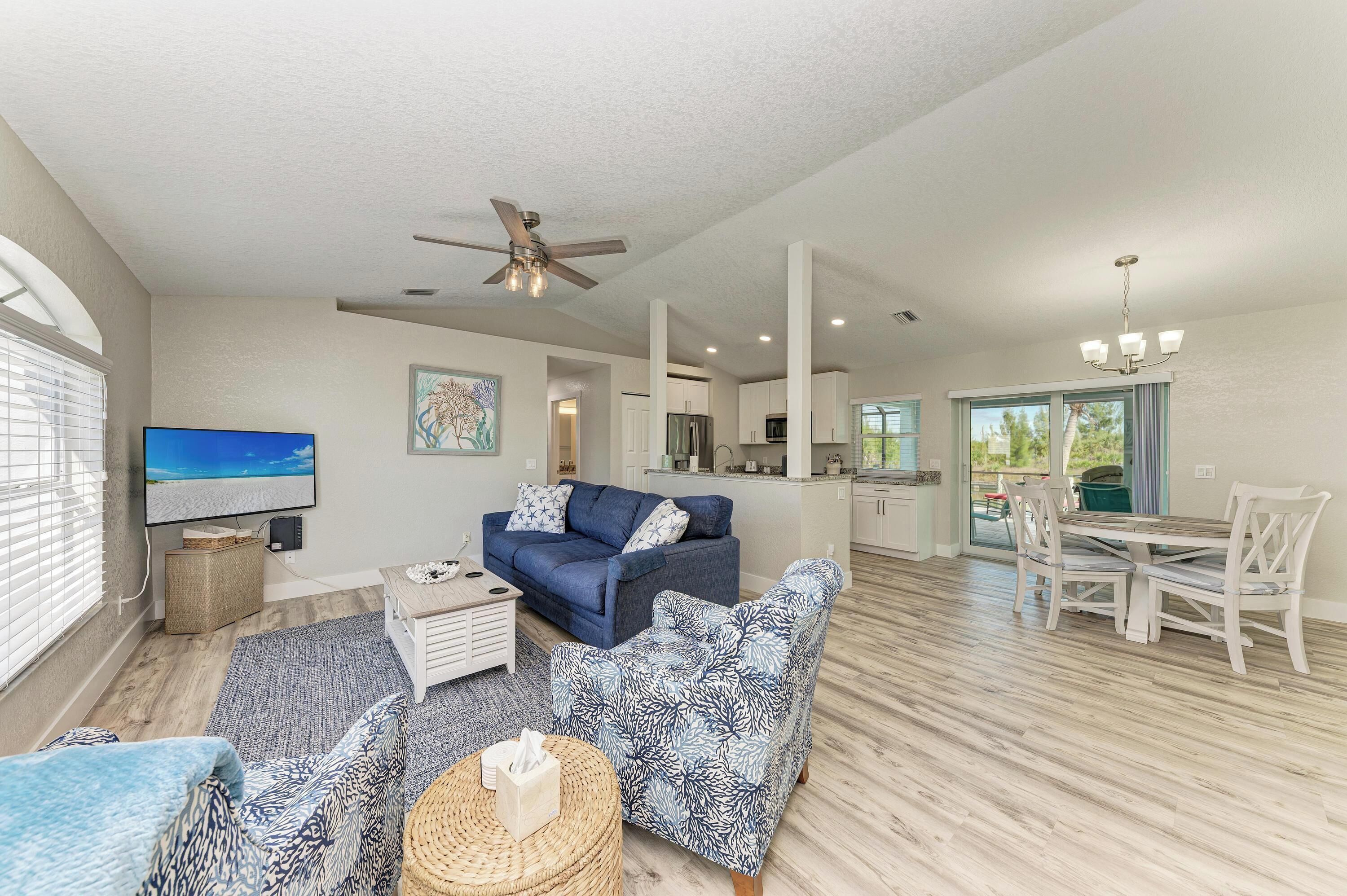 A spacious living area with a blue sofa, a television, and a dining table with chairs.