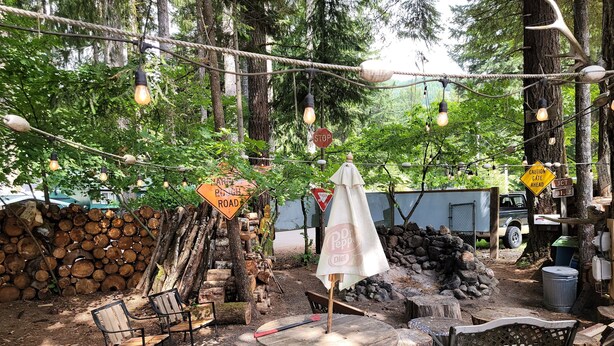 Ein Sitzbereich im Freien mit rustikalen Holzmöbeln, einem runden Holztisch und einem Baldachin.