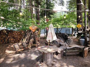 Ein Sitzbereich im Freien mit rustikalen Holzmöbeln, einem runden Holztisch und einem Baldachin.