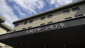A building with a sign that reads '久居グリーンホテル' indicating a hotel named 'Kujin Green Hotel'. - Hisai Green Hotel (Tsu)