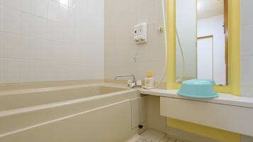 Une salle de bain avec une baignoire, un lavabo, un miroir et un porte-serviettes jaune.