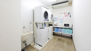 A laundry room with a washing machine, dryer, sink, and a microwave. - Hisai Green Hotel (Tsu)
