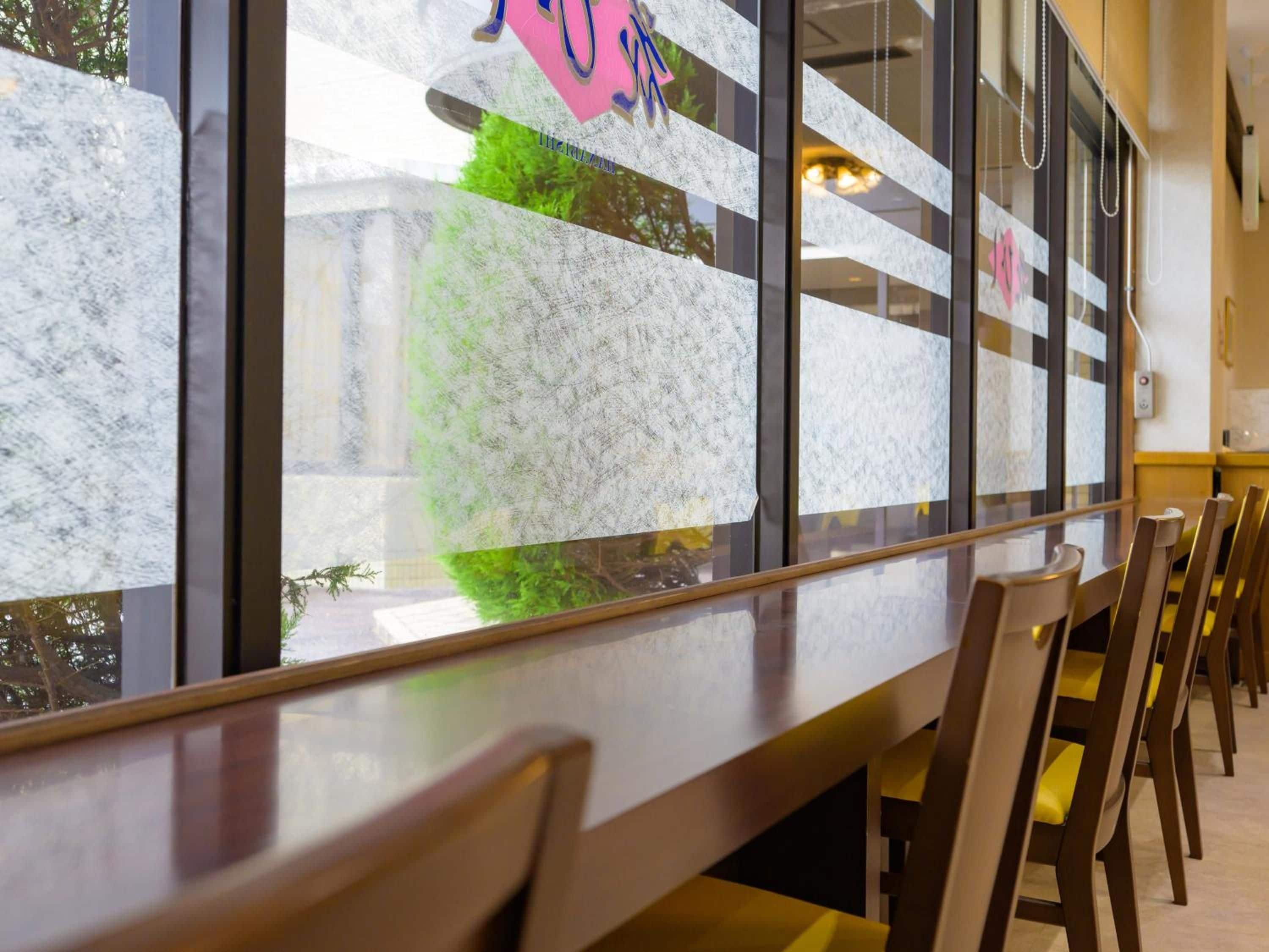 A reception area with a marble counter, wooden chairs, and a view of the outdoors through the window.