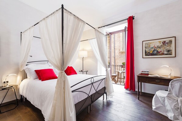 A bedroom with a four-poster bed, a desk with a chair, a lamp, and a painting on the wall. - Luxury with sea view balconies - Ortigia Beach- WiFi (Siracusa)