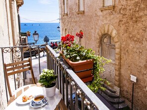 A balcony with a table set for two, potted plants, and a view of the sea. - Luxury with sea view balconies - Ortigia Beach- WiFi (Siracusa)