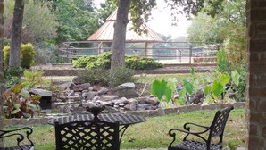 Un espace extérieur aménagé avec une table et des chaises, entouré d’un jardin agrémenté de rochers et de plantes.