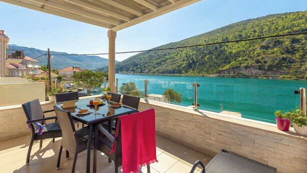 Une terrasse avec une table, des chaises et une vue sur un lac et des montagnes.