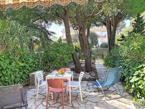 Un patio al aire libre con una mesa, sillas y un ventilador.