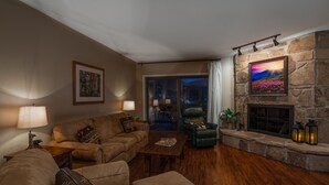 Una sala de estar acogedora con chimenea de piedra, sofás de cuero y vistas al exterior.