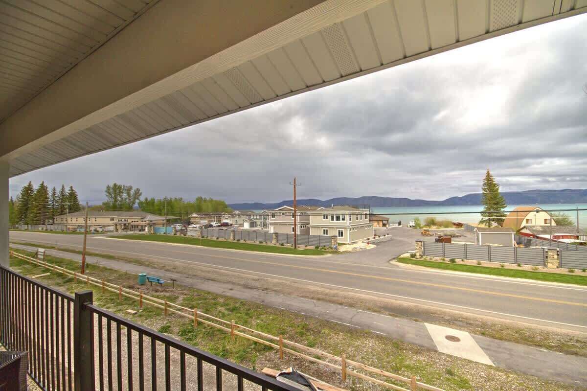 A view of a road under a bridge with buildings and a lake in the background.