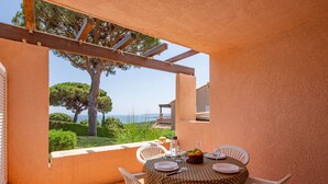 A dining area with a table set for four, overlooking a scenic view of the sea and trees.