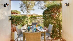 An outdoor patio with a table and chairs, surrounded by greenery and a pergola. - Mas de la Plage by Interhome (Cavalaire)