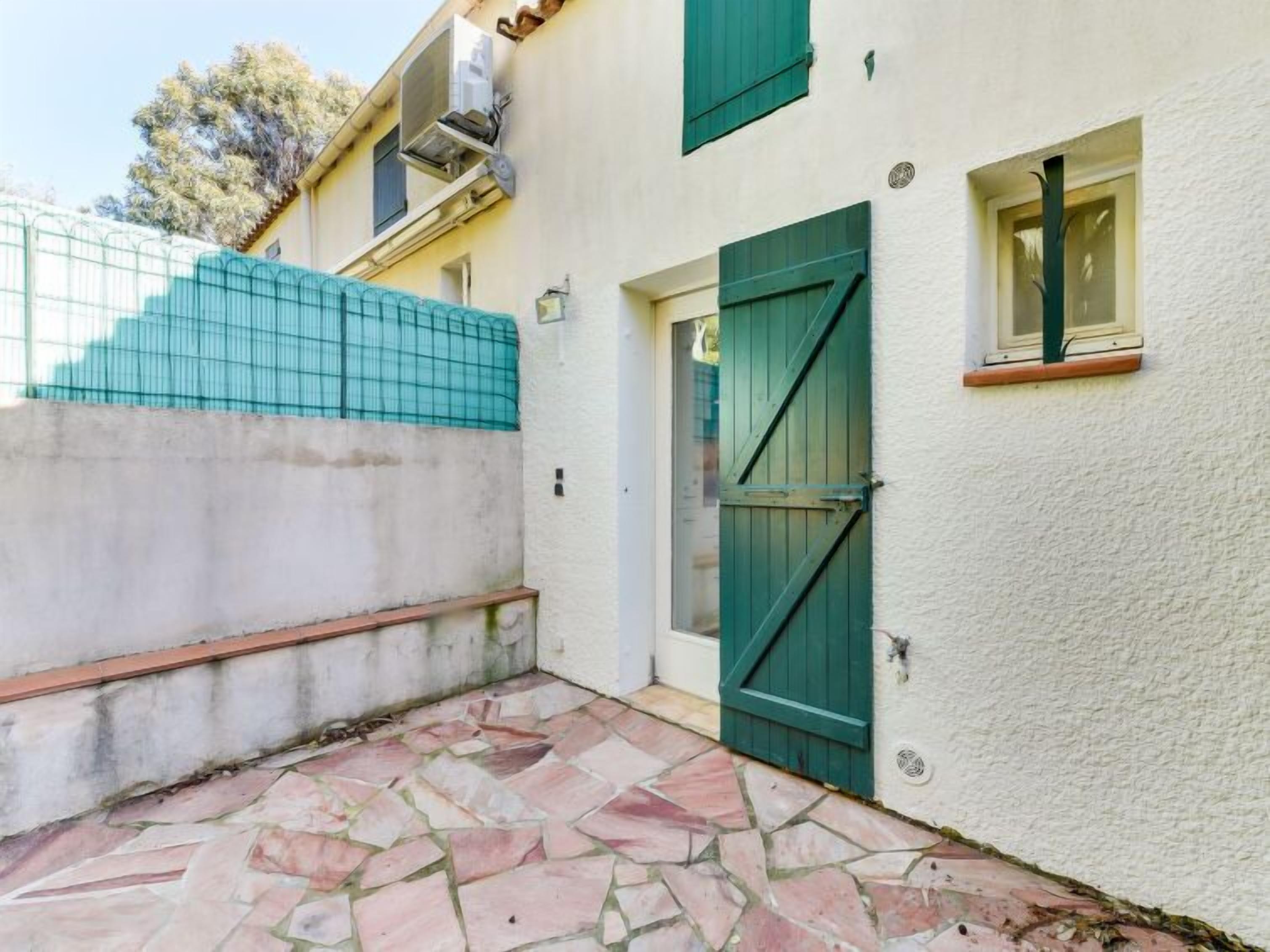 A building with a green door, a window with a wooden frame, and a tiled wall.