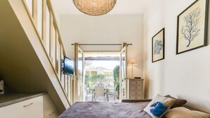 A bedroom with a bed, a television, a dresser, and a view of the outside. - Mas de la Plage by Interhome (Cavalaire)