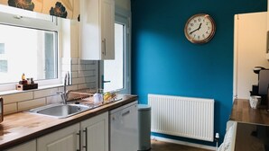 Eine Küche mit weißen Schränken, einer Spüle und einer Uhr an der Wand.