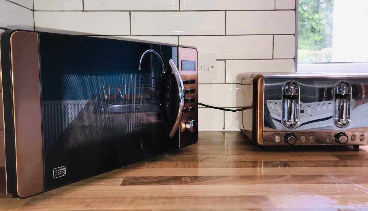 A kitchen with a black microwave and a toaster on a wooden countertop.