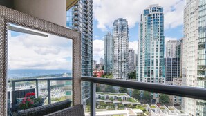 A balcony with wicker furniture, a view of high-rise buildings, and a distant marina.