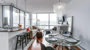 A modern kitchen with a dining area, large windows, and a city view.