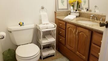 A bathroom with a toilet, a sink, and a vanity with a mirror.