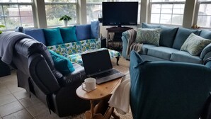 Ein modernes Wohnzimmer mit einer Couch, einem Sessel und einem Couchtisch mit einem Laptop und einer Tasse.