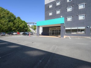 Un edificio moderno con techo plano, amplias ventanas y un estacionamiento.