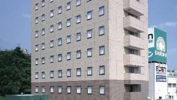 Un hotel de varios pisos con una fachada uniforme, numerosas ventanas y un letrero que indica que es un hotel.