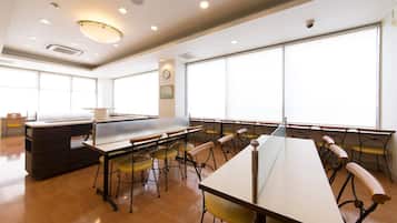A spacious room with large windows, a long table, and multiple chairs.