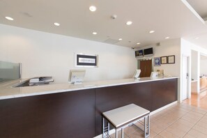 A hotel reception area with a counter, a framed sign, a television, and a security camera.
