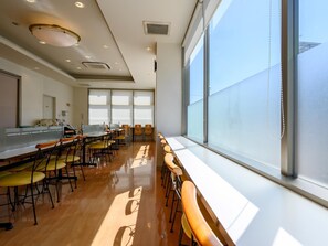 Una habitación amplia con una mesa larga y sillas, ventanas grandes e iluminación empotrada en el techo.