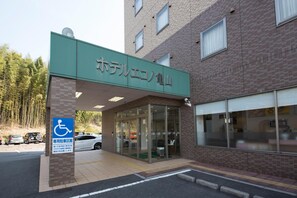 Un bâtiment avec une enseigne verte à l’entrée et un panneau indiquant qu’il est accessible aux personnes à mobilité réduite.