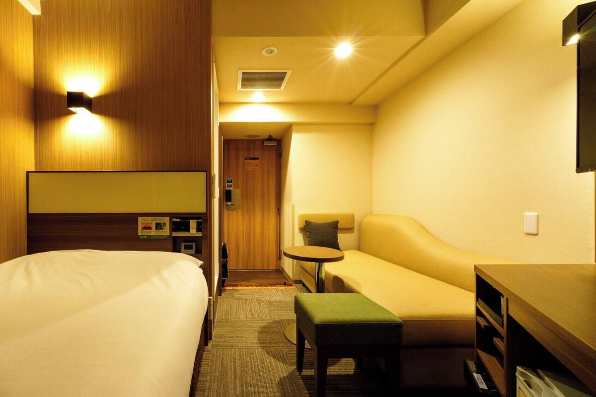 Una habitación de hotel con una cama, un sofá, una mesita y un televisor.