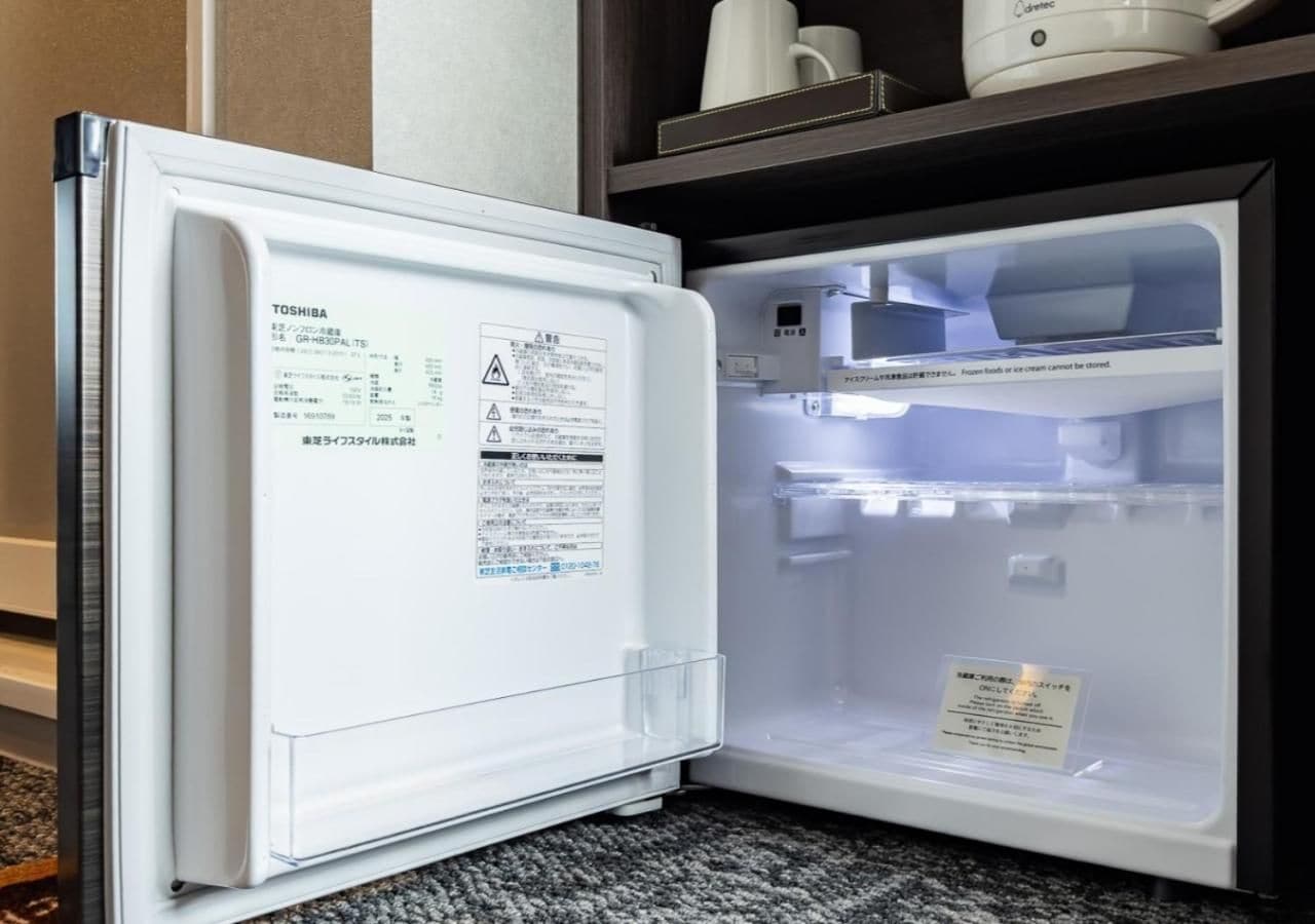 Un réfrigérateur ouvert, avec une étiquette d’avertissement sur la porte et un mot à l’intérieur.