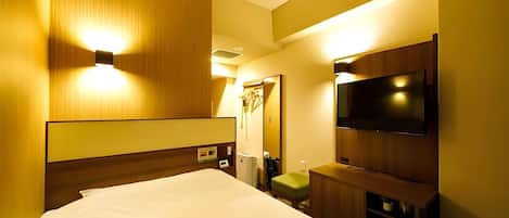 A hotel room with a large bed, a flat-screen TV, a mirror, and a wooden wardrobe.
