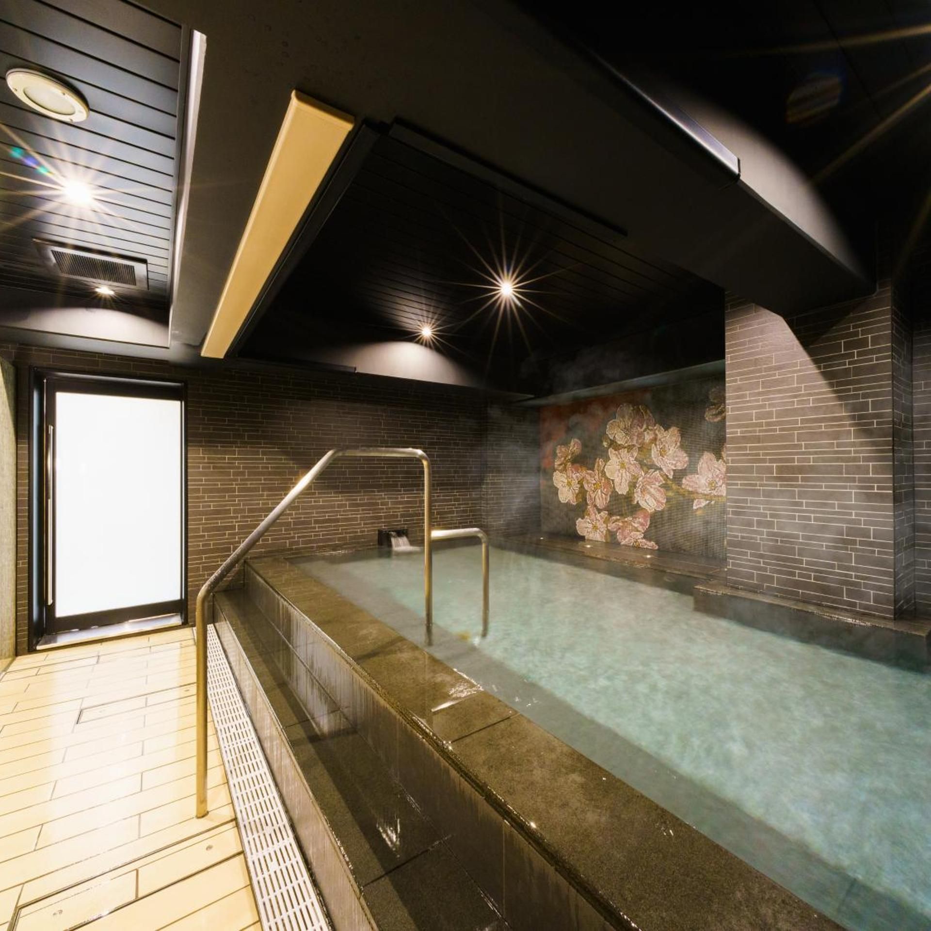 Un área de spa con un jacuzzi, una entrada con puerta de vidrio y una pared de ladrillo con papel tapiz floral.