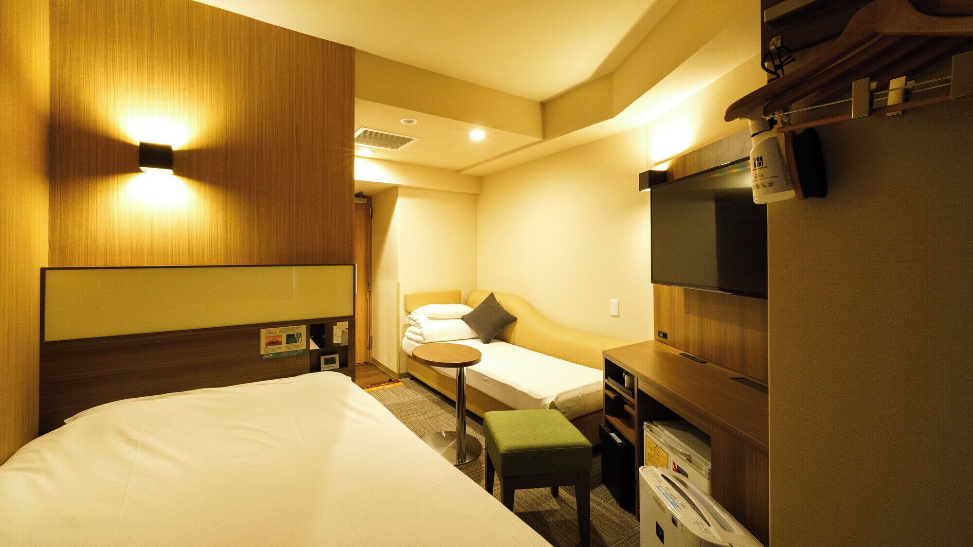 Une chambre d’hôtel avec un lit, un petit bureau, une télévision et un canapé.