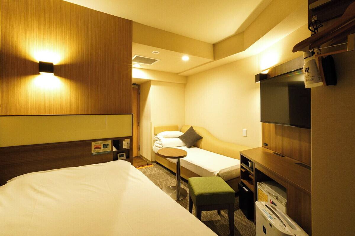 Una habitación de hotel con una cama, un escritorio pequeño, un televisor y un sofá.