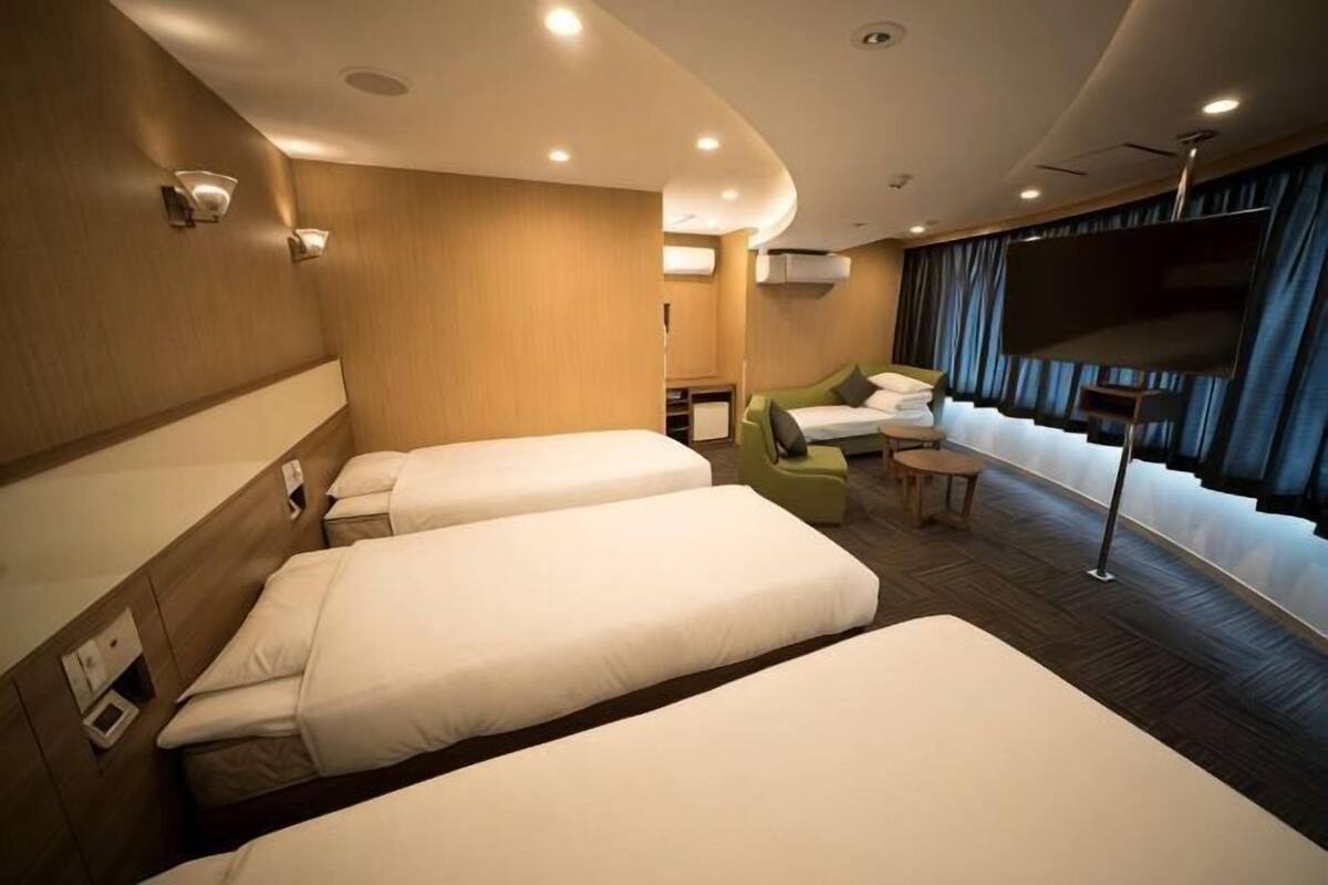 Habitación de hotel con dos camas, televisión, escritorio y ventana con cortinas.