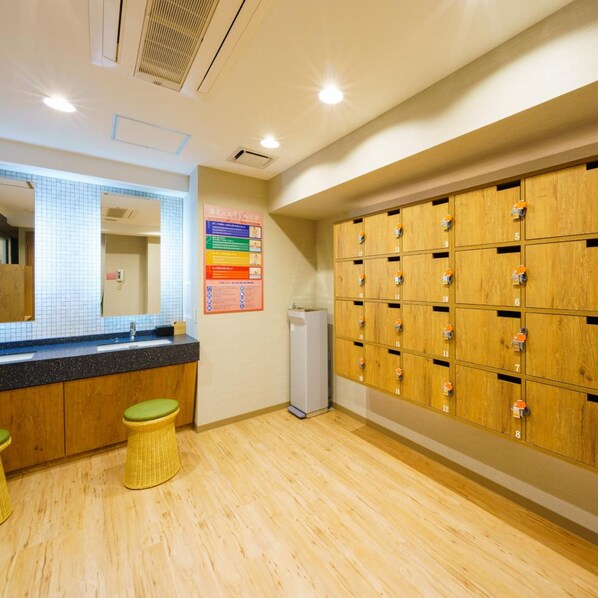 Baño con taquillas de madera, un espejo, un lavabo y un tablón de anuncios.