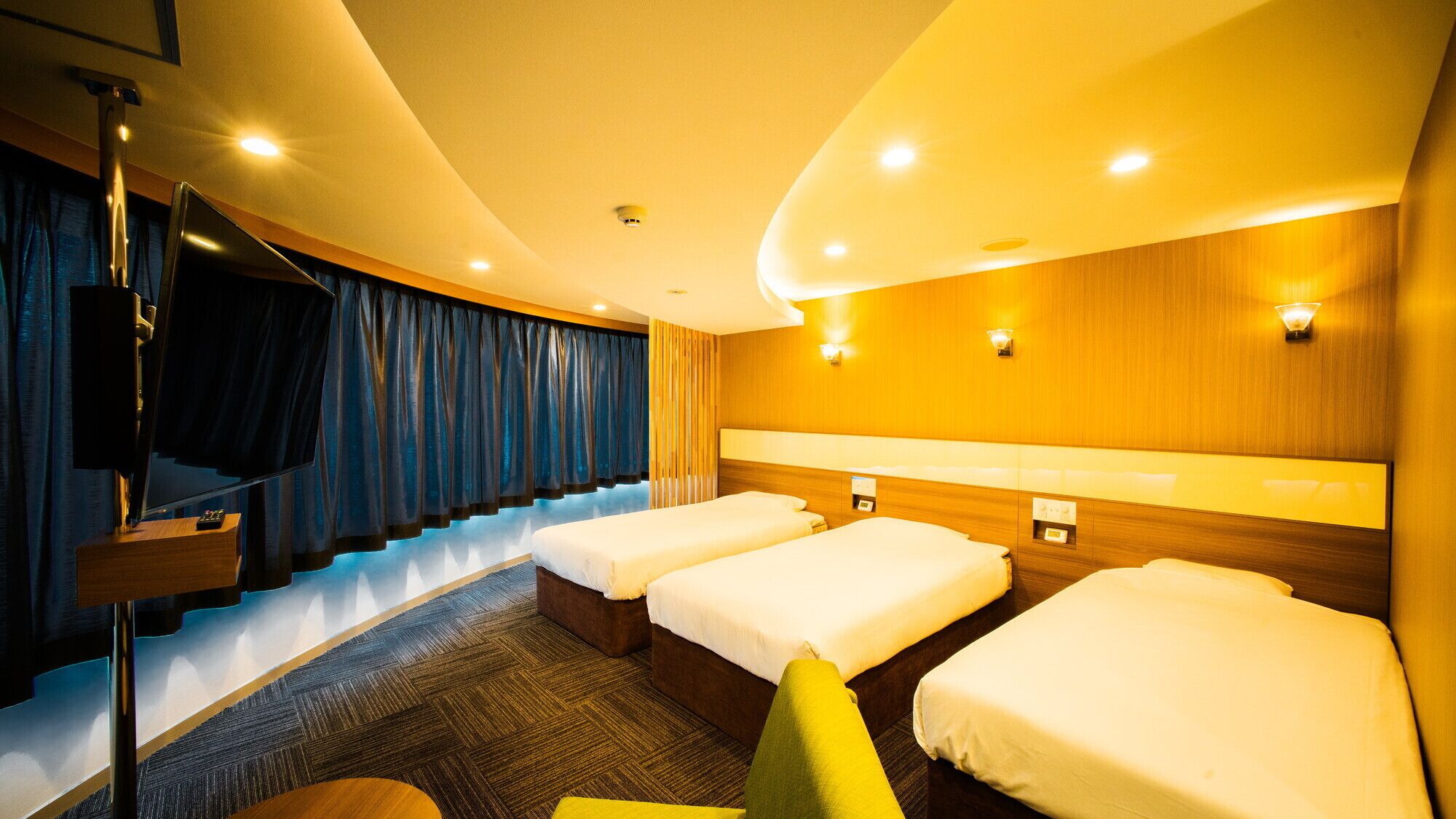 A hotel room with a curved ceiling, three beds, a TV, and a staircase.