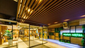 A modern hotel lobby with a wooden ceiling, glass walls, and a reception desk. - Super Hotel Ikebukuro-Eki Kitaguchi (Tokyo)