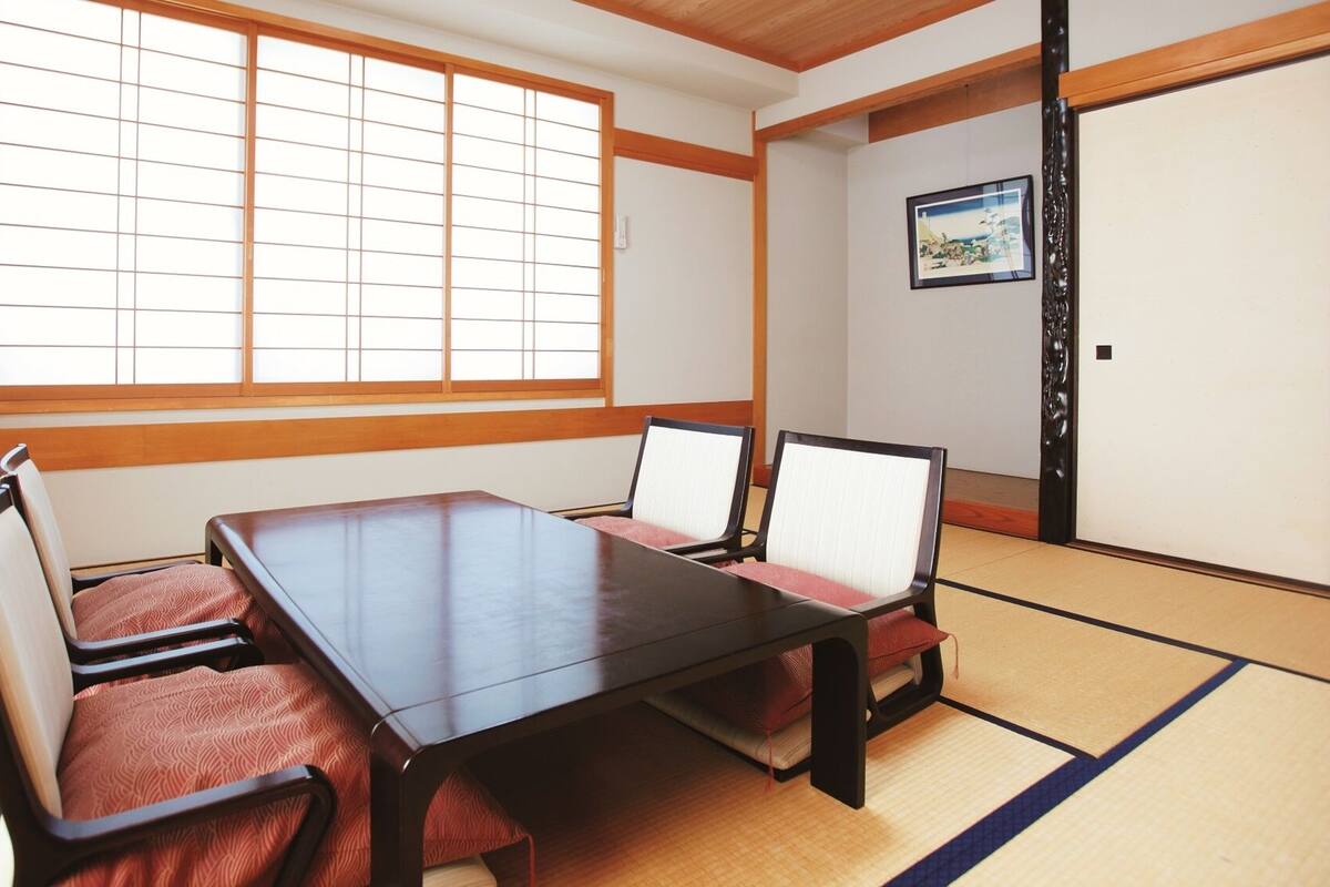 A tatami mat room with a low wooden table and four tatami mats with cushions.