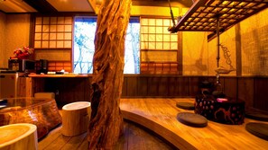 Una habitación tradicional japonesa con suelo de tatami, una mesa de madera y un llamativo centro de mesa con el tronco de un árbol.