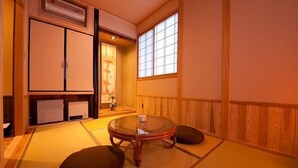Et traditionelt japansk rum med tatamimåtter, et lavt bord med hynder og skydedøre.