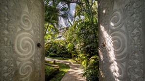 Un sentier qui traverse un jardin luxuriant, dont les murs sont ornés de sculptures complexes en pierre.