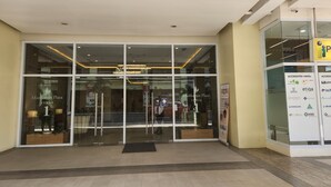Fachada de hotel de vidrio, cartel con logotipos y piso de baldosas.