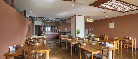 A spacious dining area with wooden tables and chairs, a central island with a sink, and a ceiling with a geometric pattern.