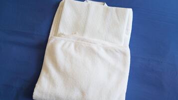 A folded white towel on a blue bedspread.