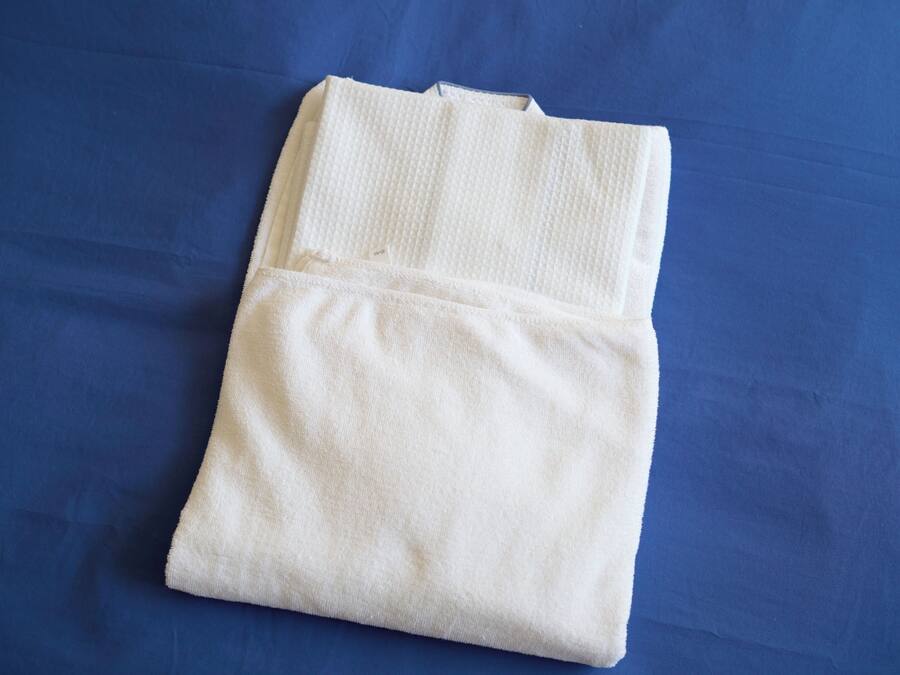 A folded white towel on a blue bedspread.